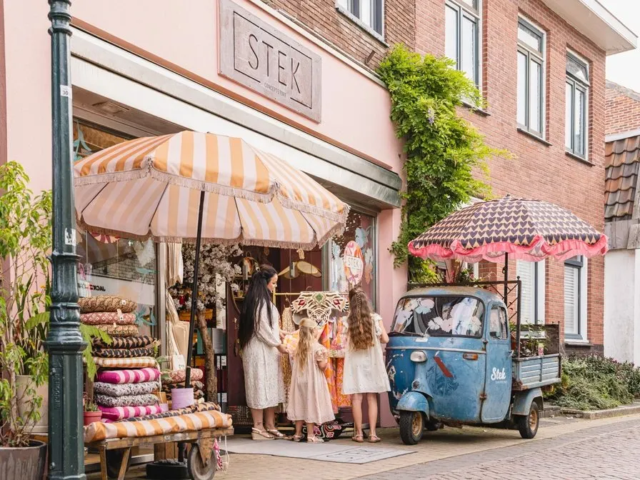 Winkelpui met parasols, kleurrijke koopwaar en een blauwe Ape