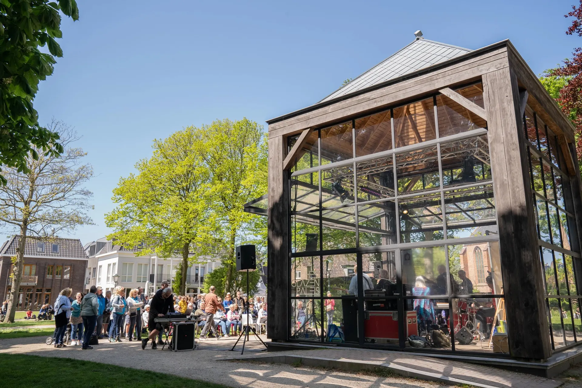 Glazen paviljoen in het park met livemuziek en publiek