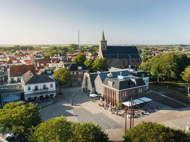Luchtfoto van het plein in Den Burg met de kerktoren en terrassen